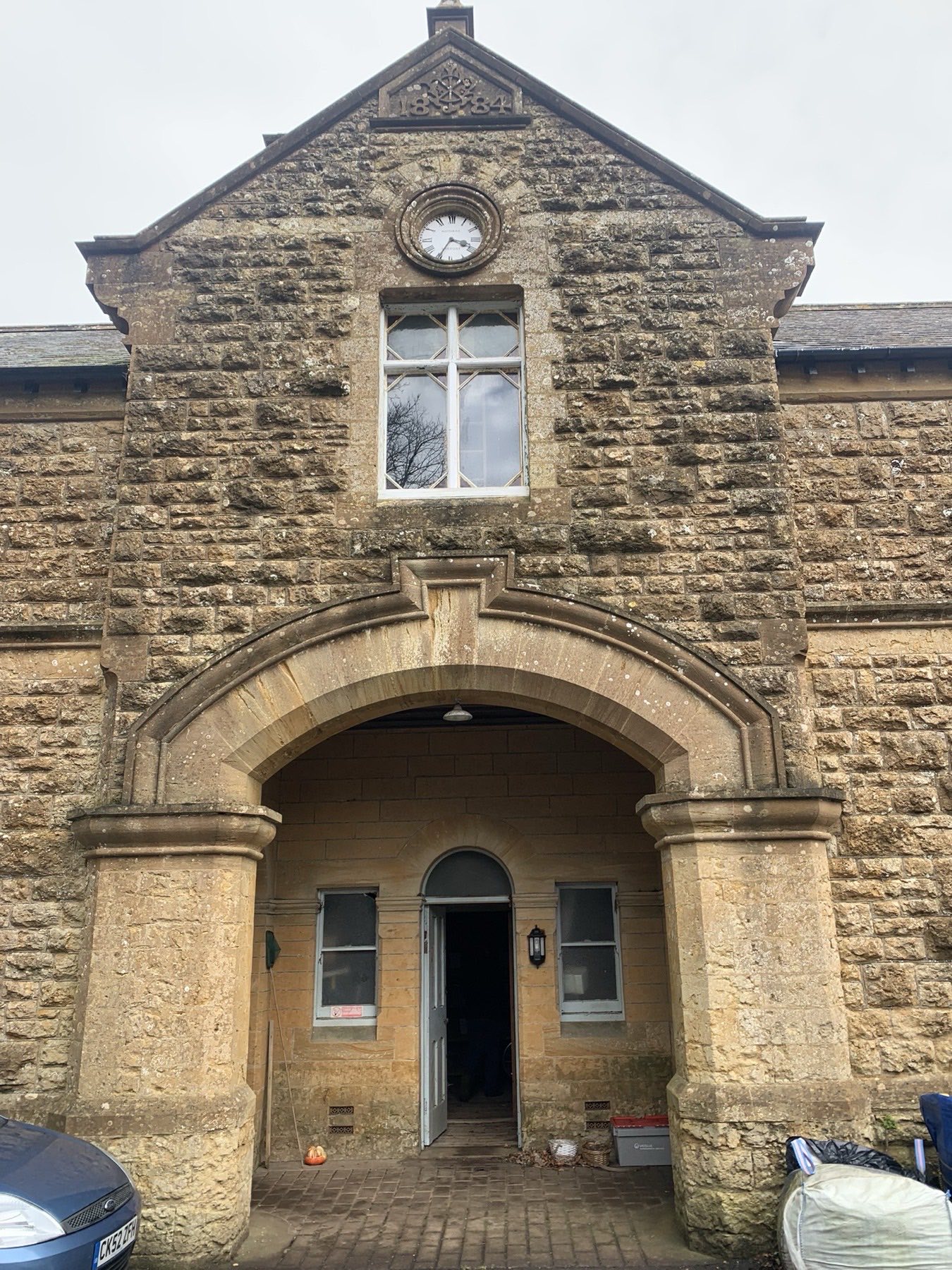 The 1884 stone stable block at Walditch, Dorset — clock tower and arched entrance, consented for conversion by Set Square Studio